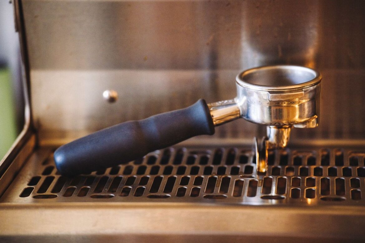 Metal espresso portafilter resting on a machine drip tray