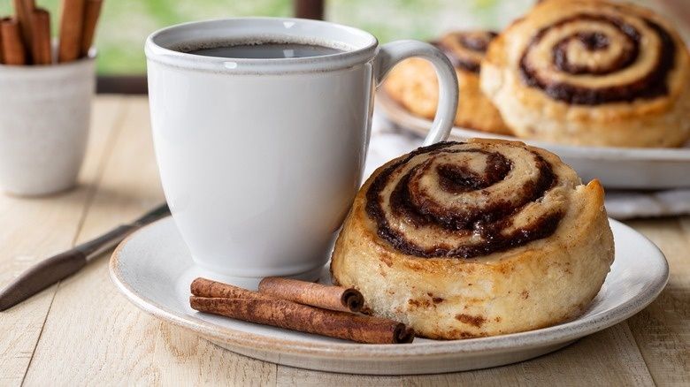 White coffee cup and cinnamon bun arranged for a Swedish fika pause