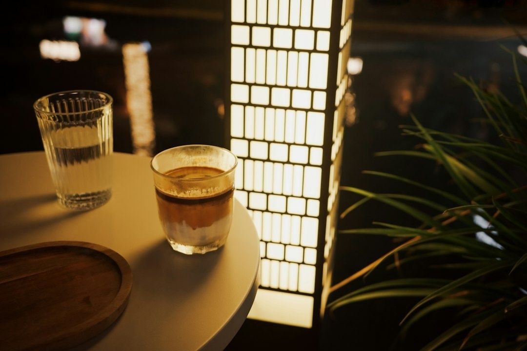 Coffee and water on a small café table beside a glowing lamp