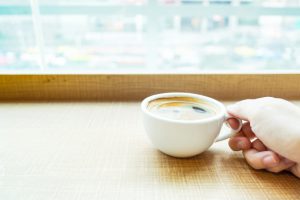 woman hand holding Espresso Coffee cup on wood table in cafe with blur city background, Leisure lifestyle concept.