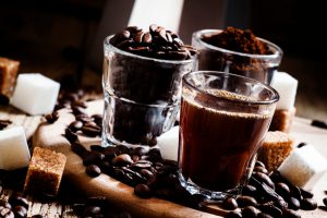 Three types of coffee: Grinded Arabica coffee beans, freshly brewed espresso, steel geyser coffee maker, vintage wooden background, selective focus